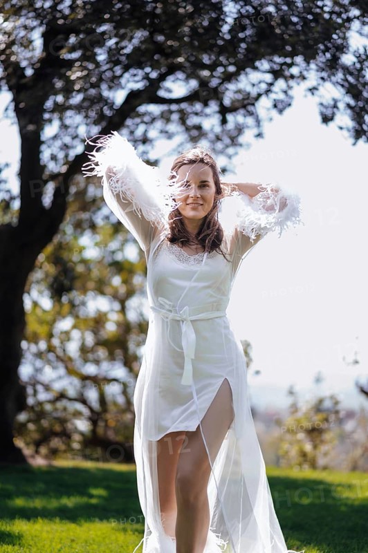 A bride in a white dress stands beautifully in a sunlit garden of an ancient villa in Treia, Macerata. The setting captures the elegance of a traditional Italian wedding