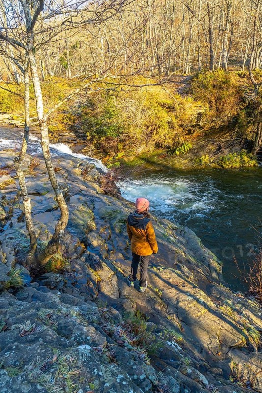 Female hiker admiring the zaldibartxo waterfall in the gorbeia natural park, basque country, spain, during a sunny autumn day