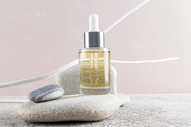 A sleek dropper bottle of skincare rests on smooth stones, evoking a sense of calmness and luxury Perfect for promoting beauty products or wellness themes