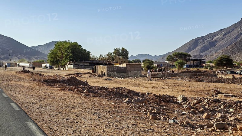 Small village in dry desert landscape with mountains and clear sky, settlement in the Sahara in Algeria