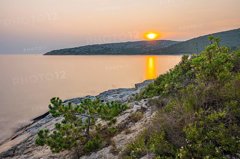 Sunset over crystal clear water on the beach of Ustrine Bay on the island of Cres, long exposure, Croatia