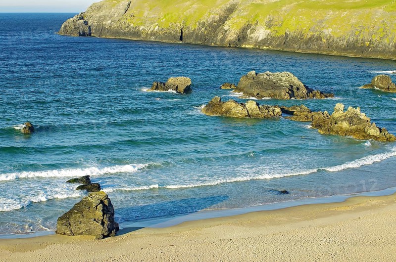 Rocky coastline with blue sea, breaking waves and huge rocks under clear skies, Durness, Highlands, Scotland, Great Britain