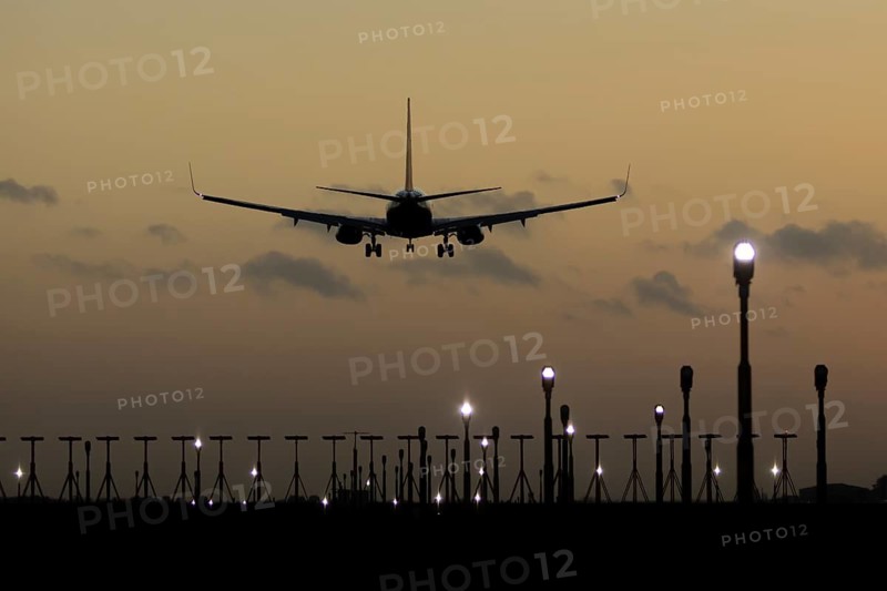 Boeing 737 commercial passenger airliner jet aircraft of Ryanair airways in flight on approach to land over runway lights at sunset at London Stansted airport, Essex, England, United Kingdom