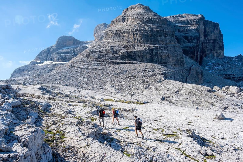 Three mountaineers on a hiking trail on the Grosté Plateau, Brenta Mountains, Parco Naturale Brenta-Adamello, Trentino, Italy