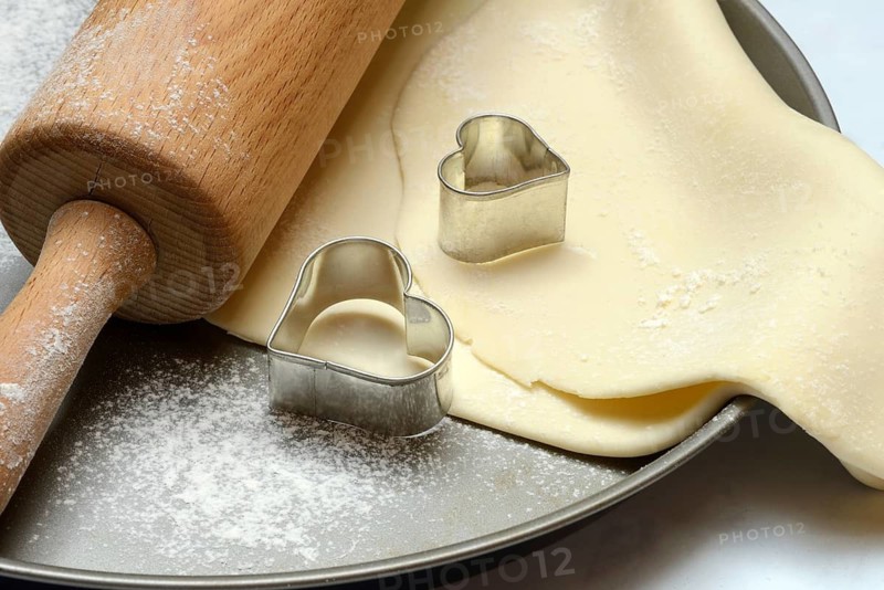 Rolled dough on cake tray with dough rollers and cookie cutters