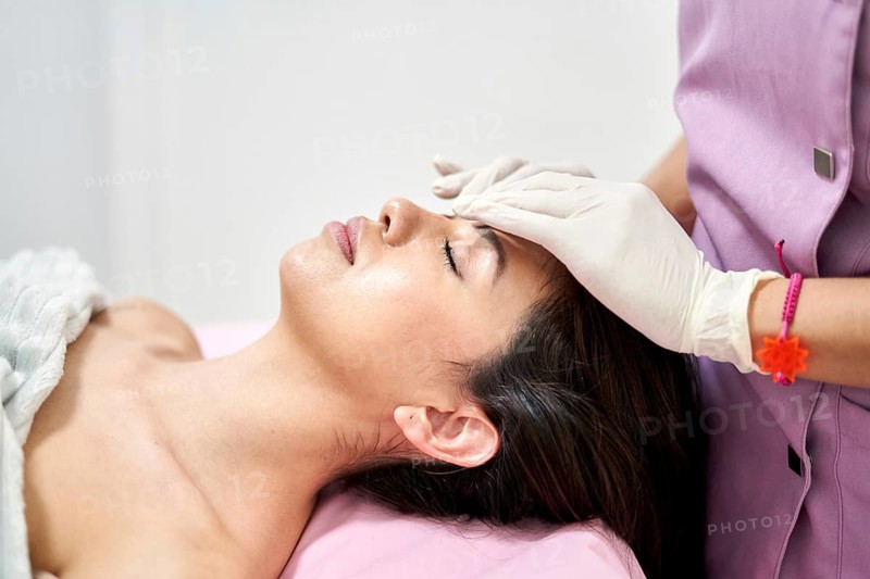 In a serene clinic of aesthetic medicine, a professional applies a facial treatment to a client. Soft lighting and calming environment enhance the beauty experience