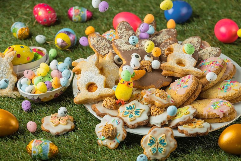 Decorated Easter cookies on a plate with colorful eggs in the grass
