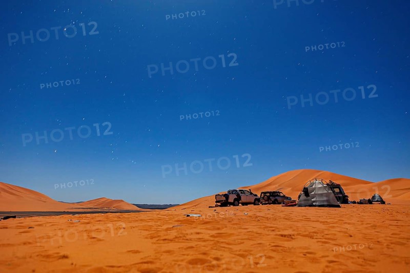 Camp in the desert under a starry night sky with tents and vehicles, tent camp in the dunes of the Sahara in Algeria