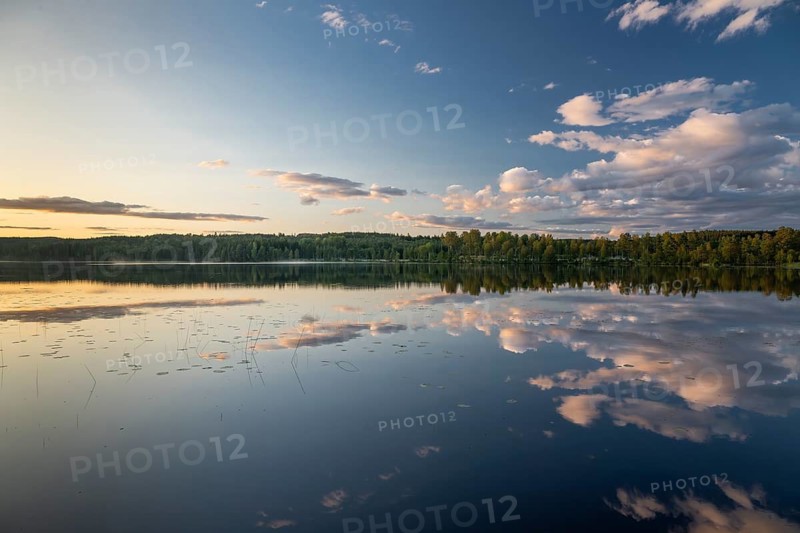 Clouds reflected on the water surface, forest lake, evening mood, at Sunne, Sweden