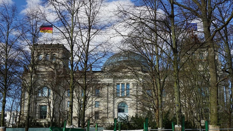 The Reichstag building with German flag and wintery trees in the foreground, Berlin
