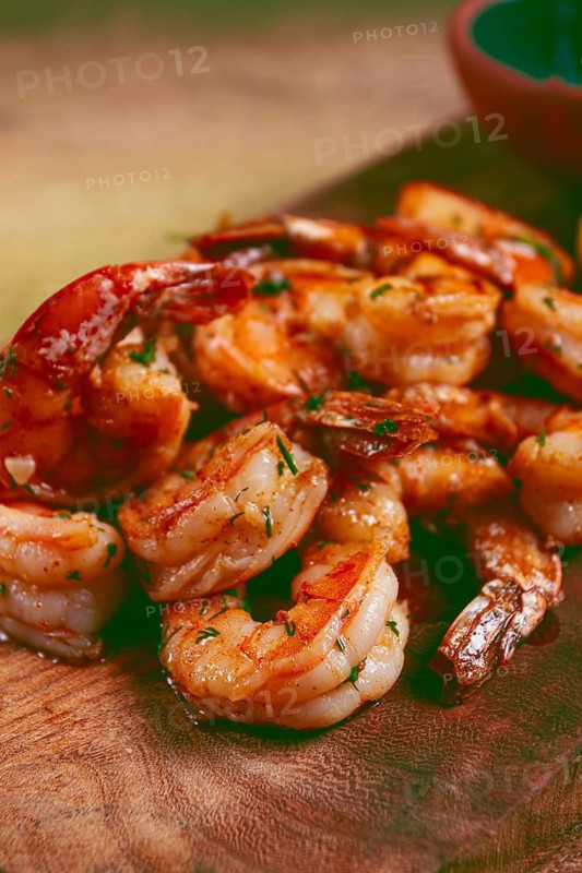 Fried tiger prawns, jumbo, in garlic sauce, in butter, with herbs, on a wooden board, homemade, no people