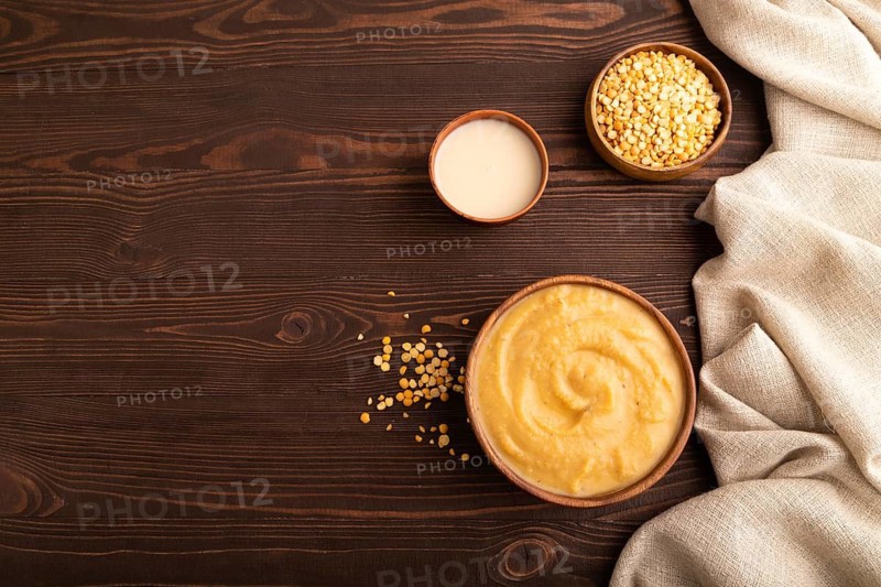 Pea cream soup, Puree, porridge in wooden bowl on wooden background and linen textile. Diet, healthy eating concept. top view, flat lay, copy space, minimalism