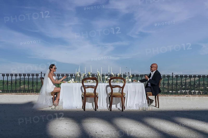 Elegant wedding reception in an ancient villa in Treia, Macerata. The outdoor setting features a beautifully set table, under a clear blue sky, with stunning Italian landscapes