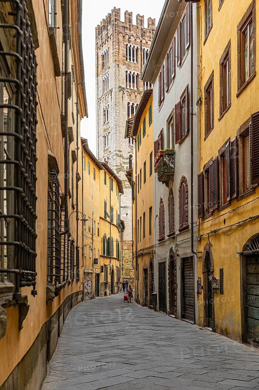 Narrow cobbled alley, houses with pastel-coloured facades, behind the tower of San Martino Cathedral, historic city centre, Lucca, Tuscany, Italy