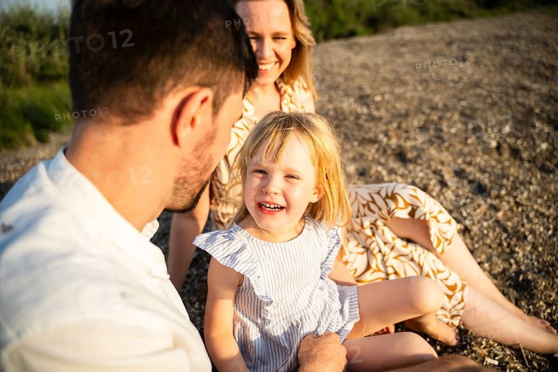 A joyful family on an Italian beach, enjoying a sunny day together. The atmosphere is warm and friendly, perfect for a relaxing vacation by the sea