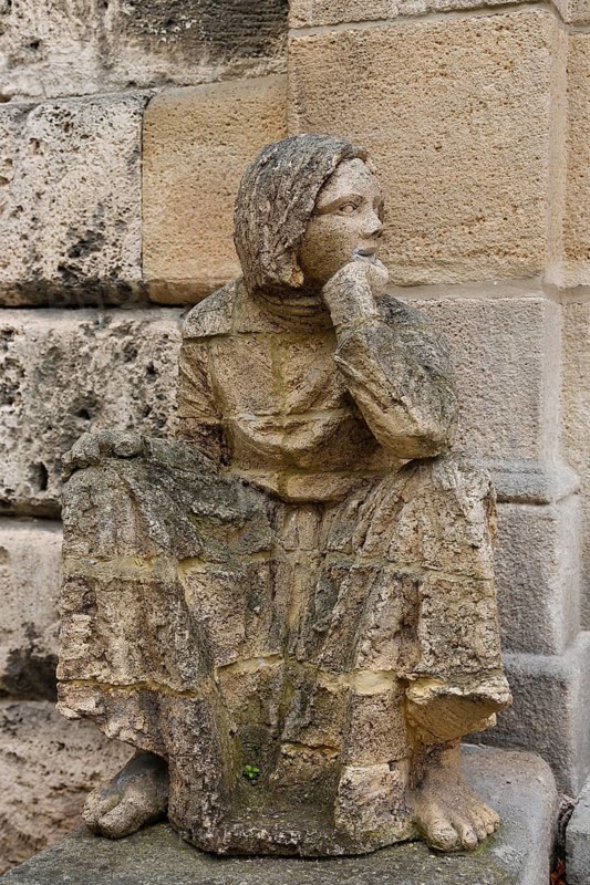 Sculpture in front of the old school building, art in public space, stone figure, sculpture by the artist Ulla Frenger, depiction of a schoolgirl, building from 1867 made of Gönningen tuff, former elementary and secondary school, today Gönningen town library branch, Gönningen, district of Reutlingen, Baden-Württemberg, Germany