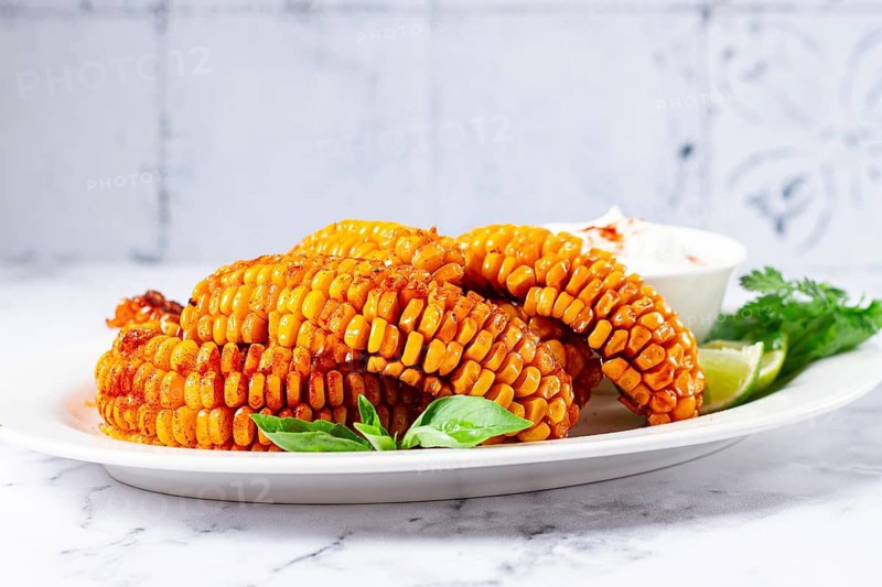 Corn ribs, with cream sauce, spices and lime, appetizer, on a white plate, homemade, no people