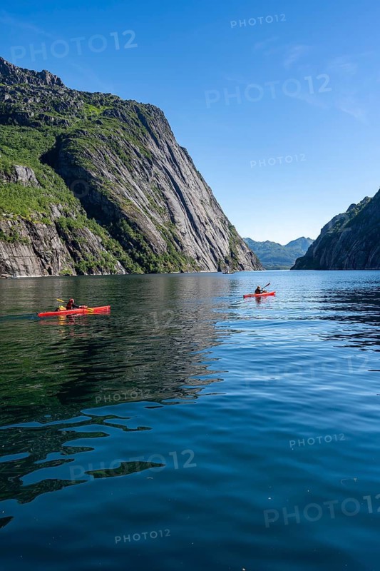 Two kayakers with red kayaks in the fjord Trollfjord, mountains reflected in the water, fjord landscape and mountains, Lofoten, Nordland, Norway