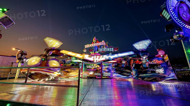 Rotating, brightly lit carousel at night at a fair, carousel and hustle and bustle of summer profit in Eisenach