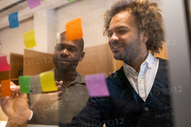 Professionals engage in a creative brainstorming session in a vibrant Barcelona coworking space, utilizing colorful sticky notes for visual organization and idea generation