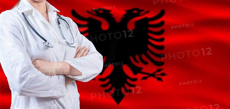 Doctor with crossed arms on Albania flag. Albania health and care concept. Female doctor on Albania flag