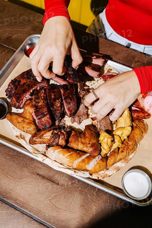 A mouthwatering barbecue platter featuring an assortment of meats, including ribs, sausage, and chicken, served on a tray. Perfect for a hearty outdoor meal