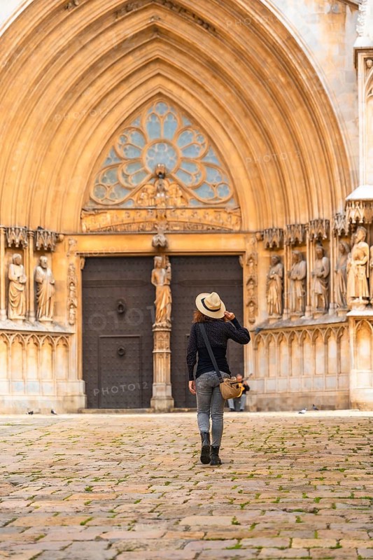 Tourist walking away from the cathedral of tarragona in catalonia, spain, admiring the medieval architecture of the city