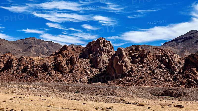 Desert landscape with rocky mountains and dry ground under a clear blue sky, The landscape of the Ahaggar Mountains in the Sahara in Algeria