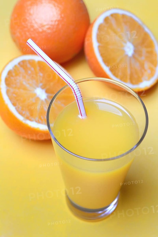 Orange juice in glass and oranges