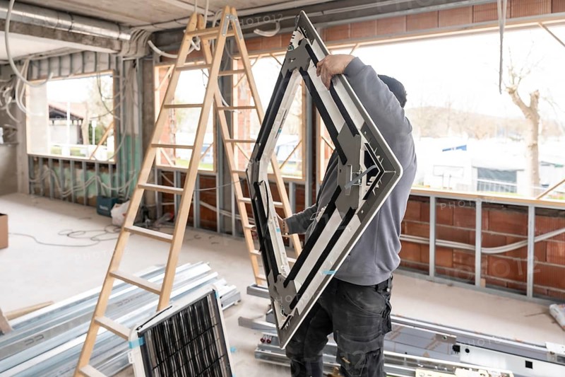 Hvac technician working on site, installing a crucial component of an air conditioning unit into a new building under construction, focusing on modern climate control systems
