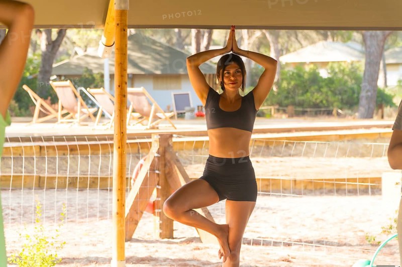 Yoga instructor practicing the tree pose, or vrksasana, during a session in a glamping resort, promoting wellness and mindfulness in a natural setting