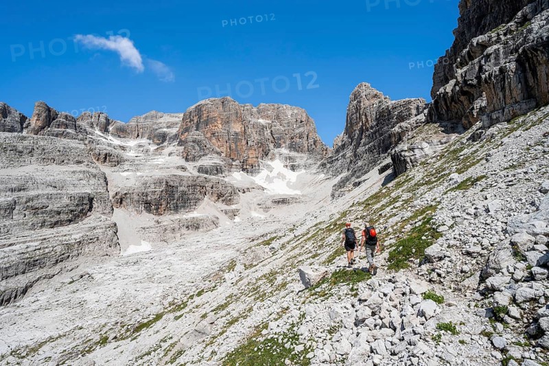 Two mountaineers on a hiking trail to Sella della Tosa, mountainous landscape in the Brenta Mountains, Brenta-Adamello Natural Park, Trentino, Italy