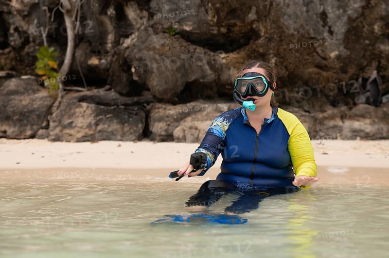 A snorkeler in vibrant gear prepares to explore the clear waters of Raja Ampat, Indonesia, known for its stunning marine biodiversity and serene island landscapes