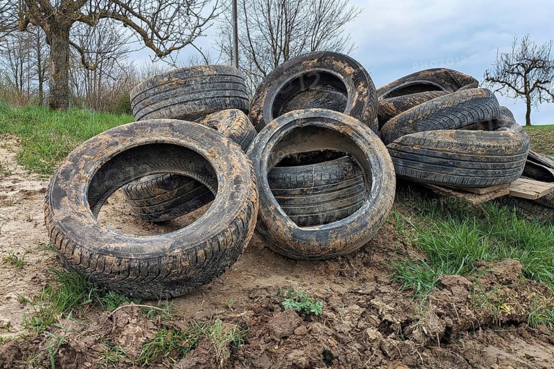 Pile of old tires dumped in nature. Illegal waste disposal and environmental pollution