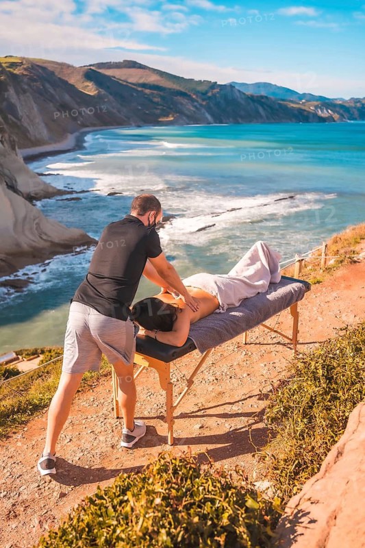 Massages in nature on the coast near the sea, masseuse with face mask in the coronavirus pandemic