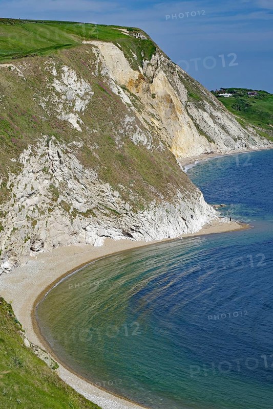 Green cliffs and rocky beach on a calm blue sea, Jurassic Coast, Weymouth, Dorset, England, United Kingdom