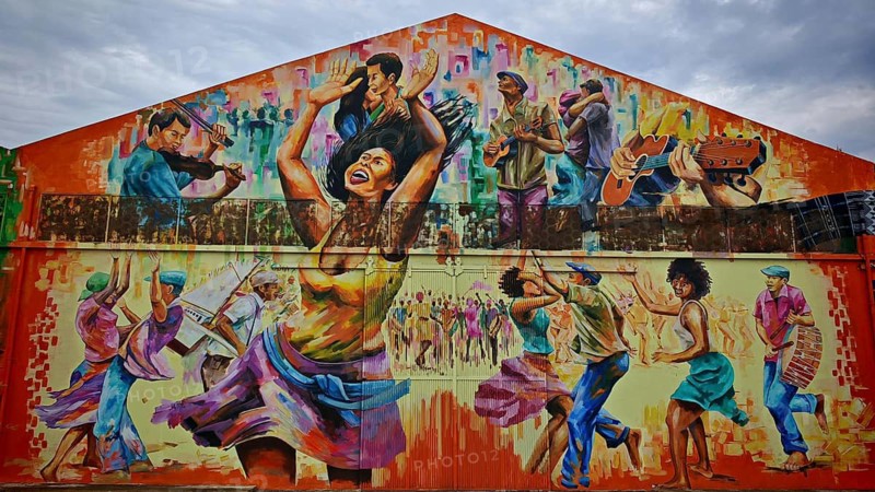 Dynamic mural, mural, graffiti showing people dancing and playing music in vibrant colors, hangar, warehouse at the port of Mindelo, Sao Vicente Cabo Verde, Cape Verde, Cape Verde