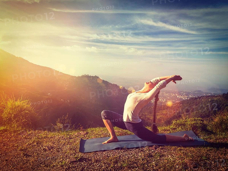 Yoga outdoors, sporty fit woman practices yoga Anjaneyasana, low crescent lunge pose outdoors in mountains in morning. With light leak and lens flare. Vintage retro effect filtered hipster style image