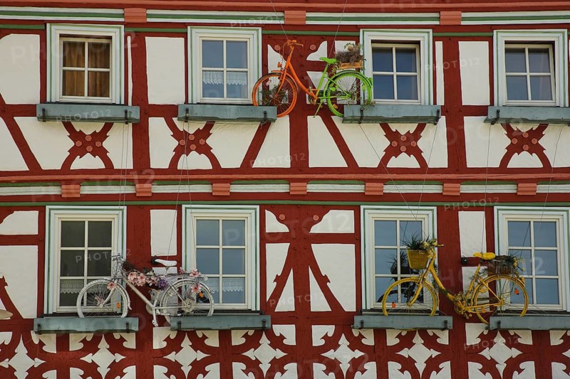 Brown-red house wall of half-timbered house with flower decoration and three bicycles as decoration, market square, Meiningen, Thuringia, Germany