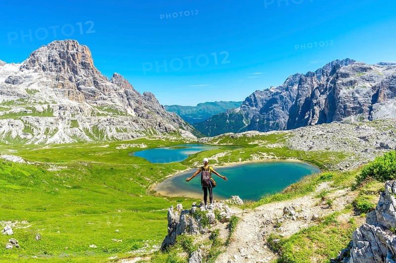 Backpacker standing with open arms, embracing the stunning view of the tre cime di lavaredo and its turquoise lakes in the heart of the italian dolomites. Laghi dei Piani