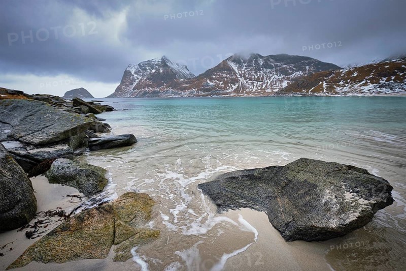 Rocky coast of fjord of Norwegian sea in winter with snow. Haukland beach, Lofoten islands, Norway