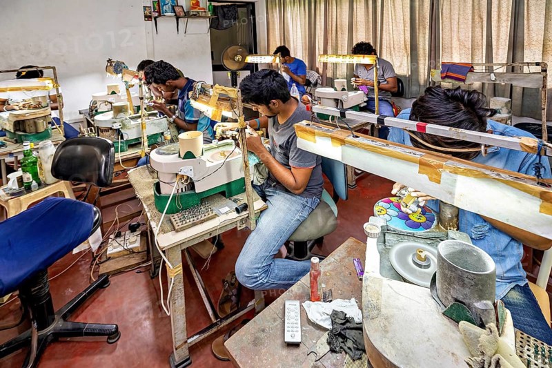 People are engaged in jewelry making, concentrated and using various tools. The sapphire and gemstone cutters at Ratnapura in Sri Lanka