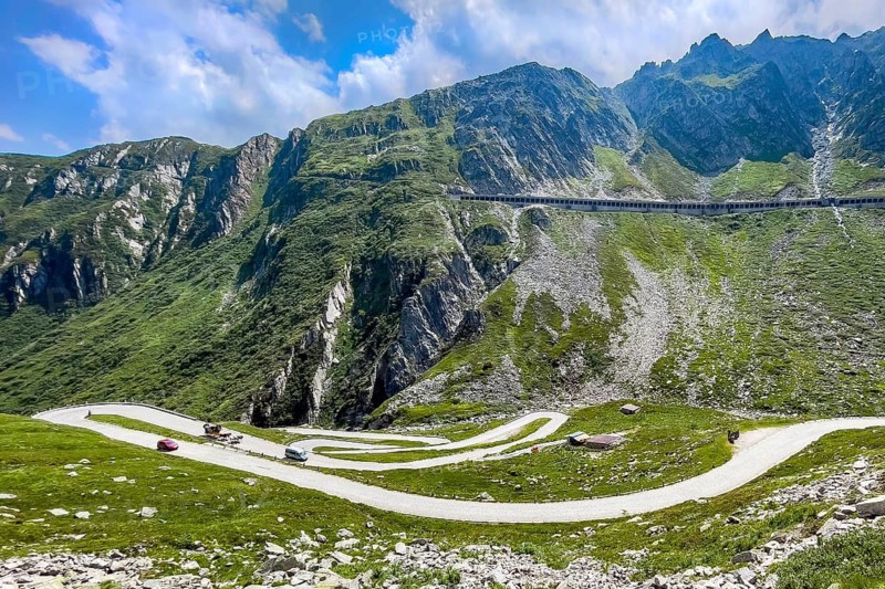 View of in the foreground serpentines hairpin bends of old historic St. Gotthard pass road Tremola Gotthardpass Alpine pass mountain road with cobblestones, in the background steep slope with modern pass road in gallery protection against rockfall and snow, Airolo, Ticino, Ticino, Switzerland