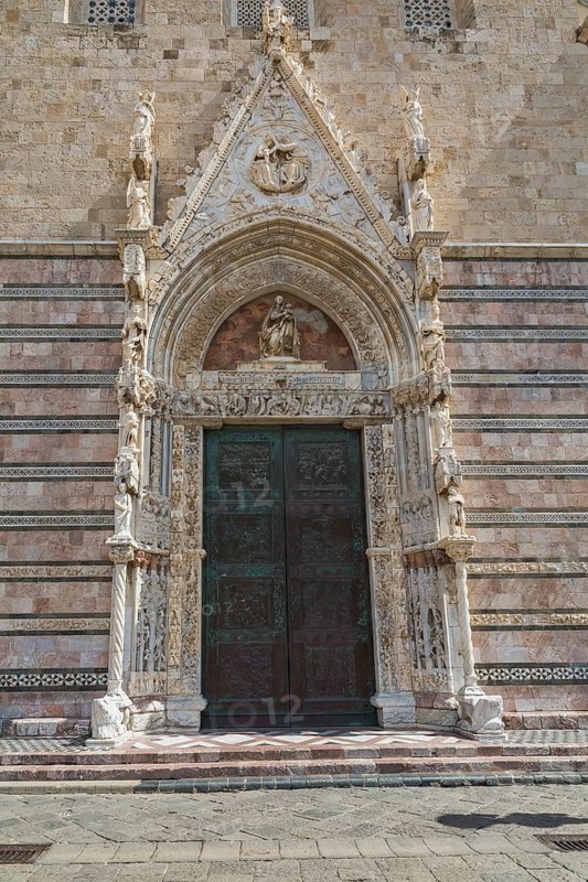 Ornate entrance door decorated with religious sculptures and figurines on facade at Messina Cathedral, Messina, Sicily, Italy