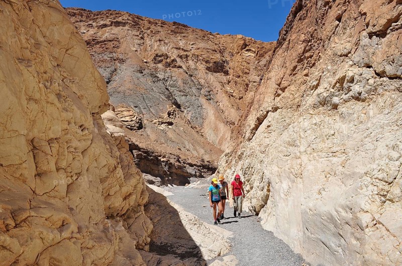 Three hikers in a narrow, sun-drenched gorge, Death Valley National Park, Mojave Desert, California, Nevada, USA