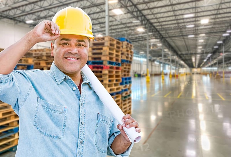 Hispanic Male Contractor Wearing Hard Hat Standing in Empty Industrial Warehouse