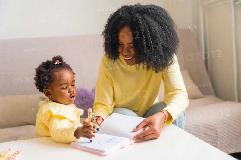 African mother and child drawing at home sitting on the sofa in the living room