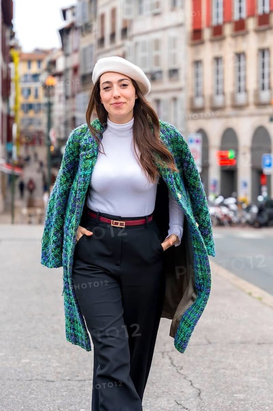 Vertical photo of a fashionable woman smiling while walking exploring a beauty city