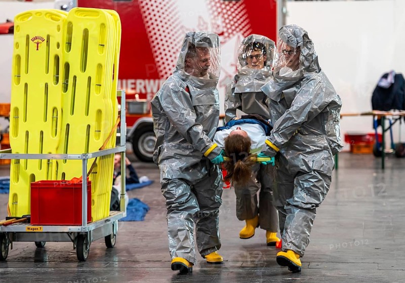 Decontamination of injured persons after an assumed accident involving hazardous substances, fire brigade and aid organisations practise setting up and operating a decontamination station, injured persons are sighted and then washed in a special shower tent to remove possible hazardous substances and chemicals in order to avoid further injuries, the emergency services wear special, ventilated protective suits, large-scale exercise by the Essen fire brigade