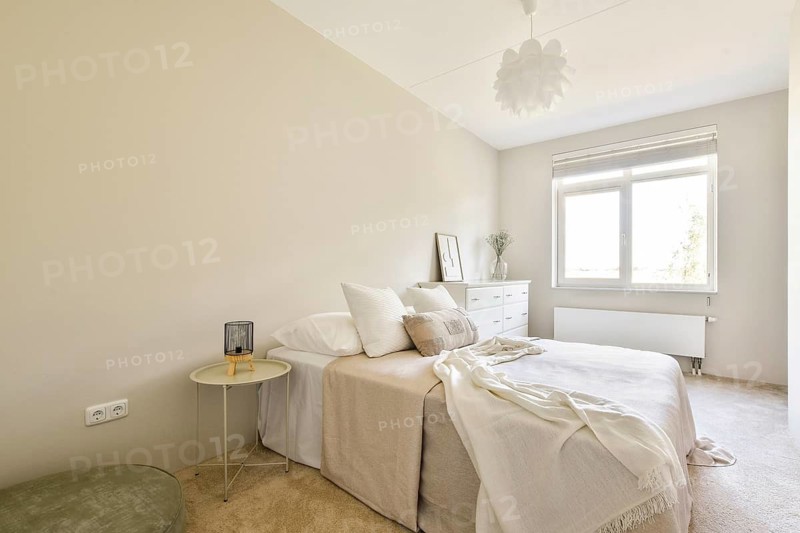 A serene and minimalist bedroom featuring soft colors, natural light, and simple decor, creating a peaceful atmosphere for relaxation and comfort
